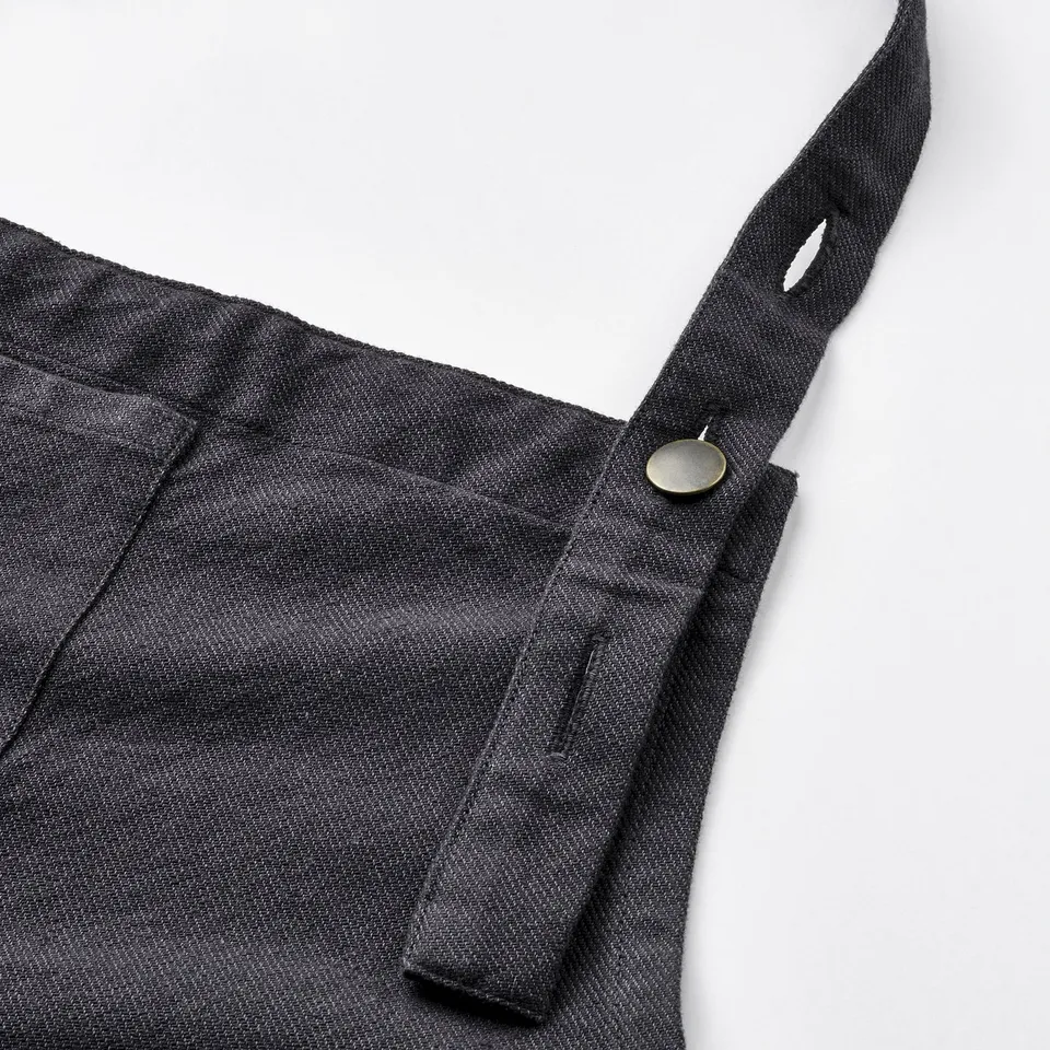 High-quality grey apron close-up, showing adjustable neck strap and sturdy pocket with metal button.