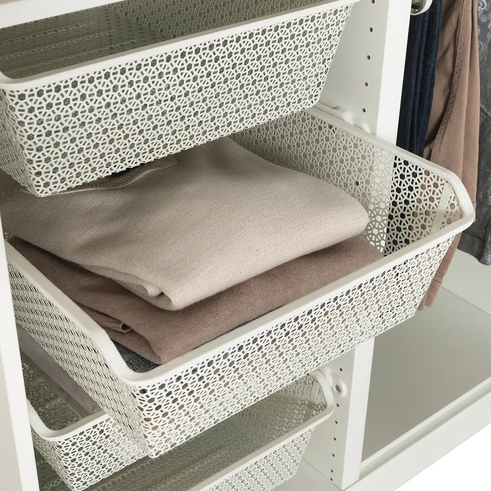 White metal wardrobe baskets holding folded clothes, organising and allowing air circulation.