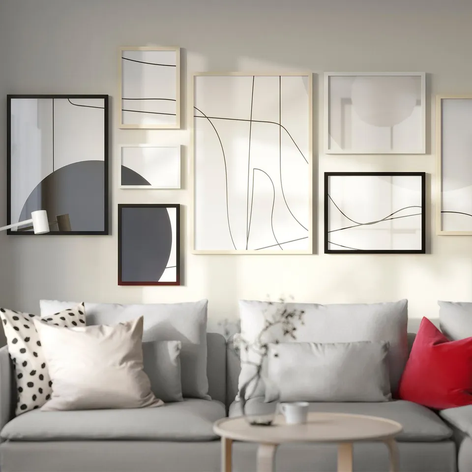 Modern living room with grey couch, colourful pillows, eclectic gallery wall, and table with flowers and a mug.