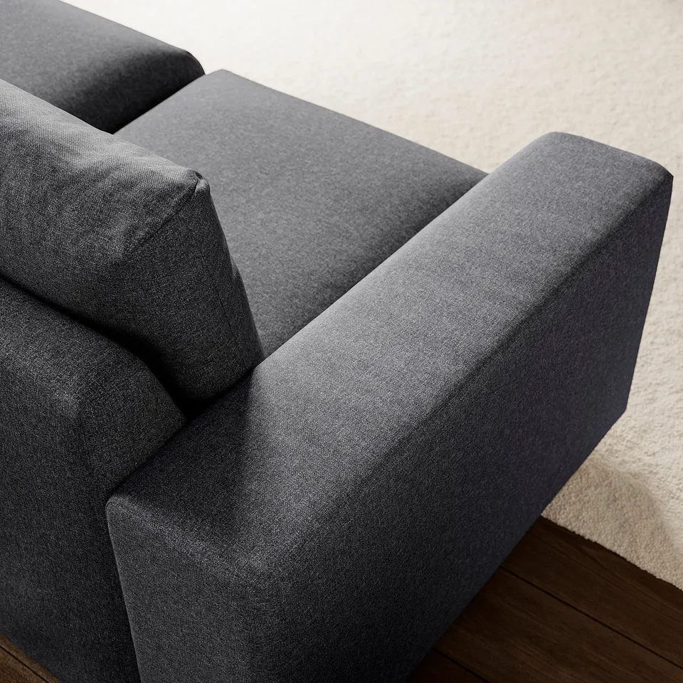 Modern grey sofa, bold clean lines, plush cushions, sturdy wooden floor.
