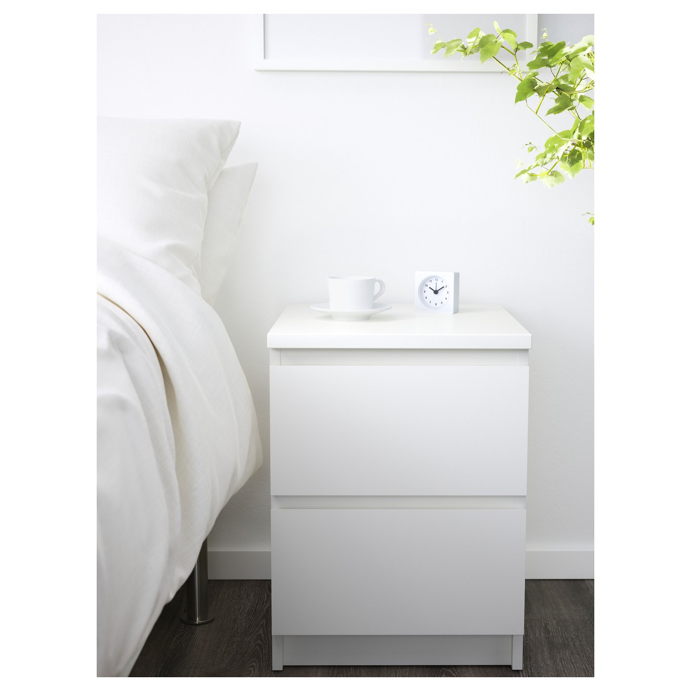 White MALM bedside table with 2 drawers, cup, and clock.