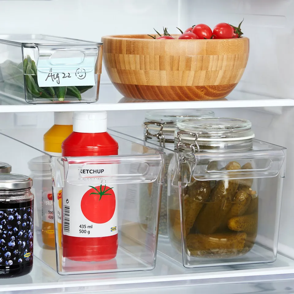 Fridge with clear plastic boxes; ketchup, pickles, tomatoes; stackable & organised.
