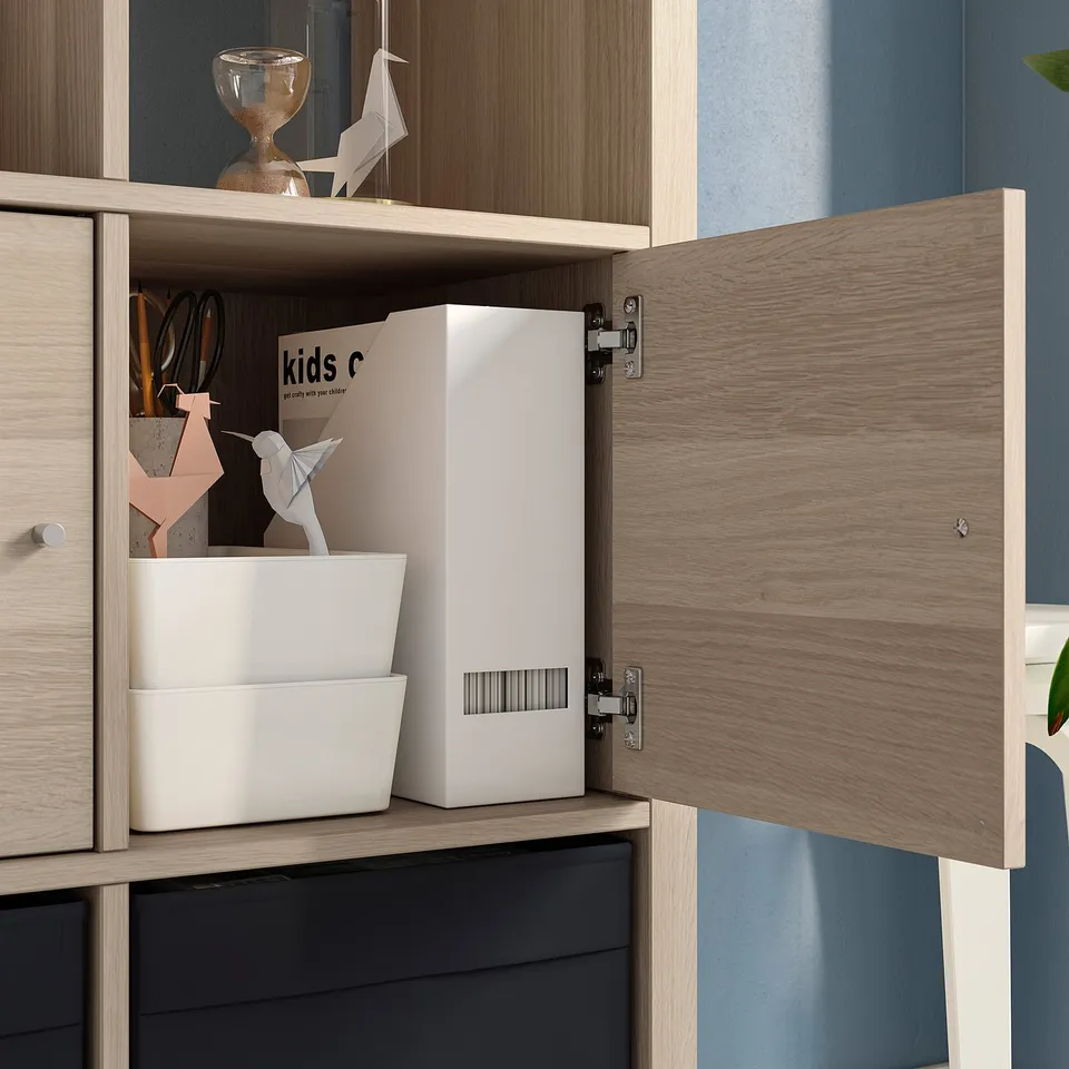 Cabinet with open door revealing storage boxes and paper crafts, mounted on a wall with dark blue background.