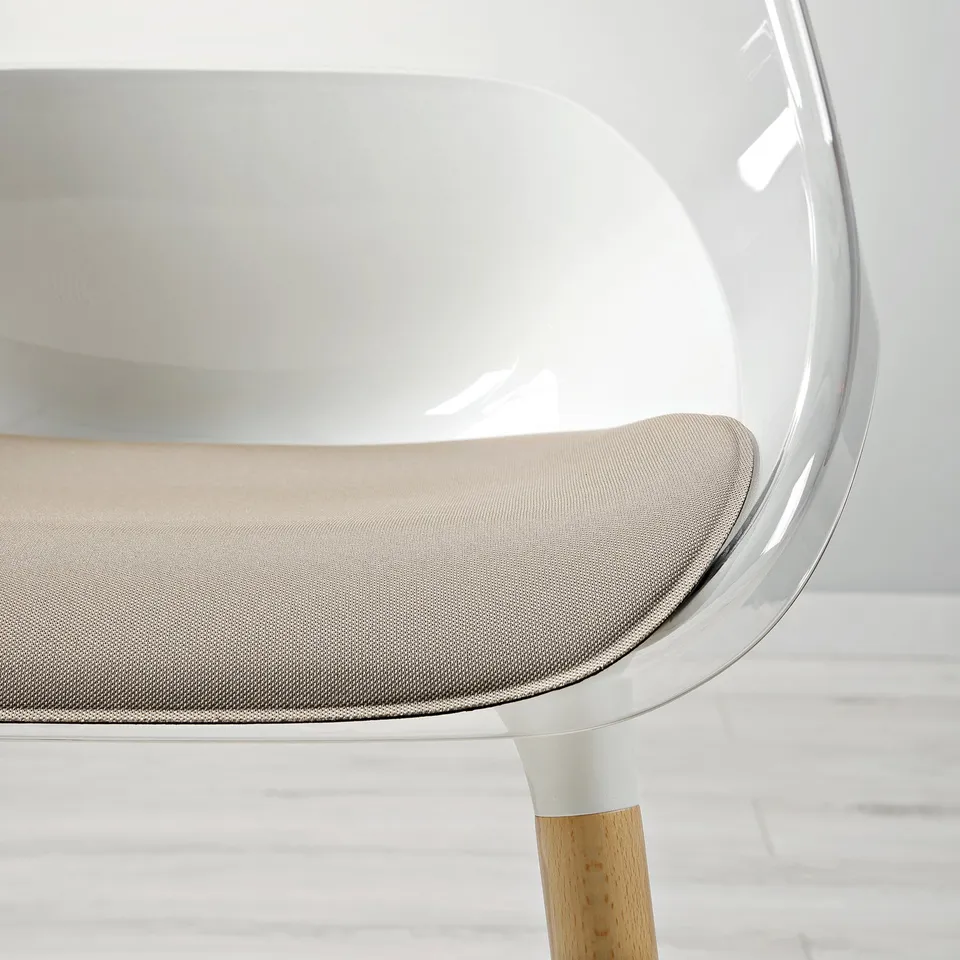 Modern chair with clear seat, curved back, wood legs, plush cushion.