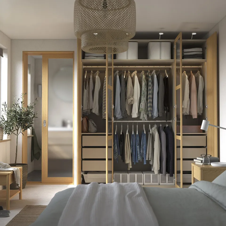 Bedroom with open wardrobe showing clothes, shelves, and lighting.