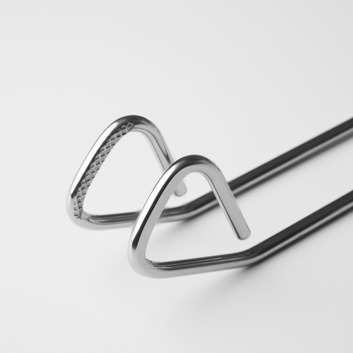 Stainless steel tongs with textured grips; one bent over the other, showcasing sturdy design and quality.