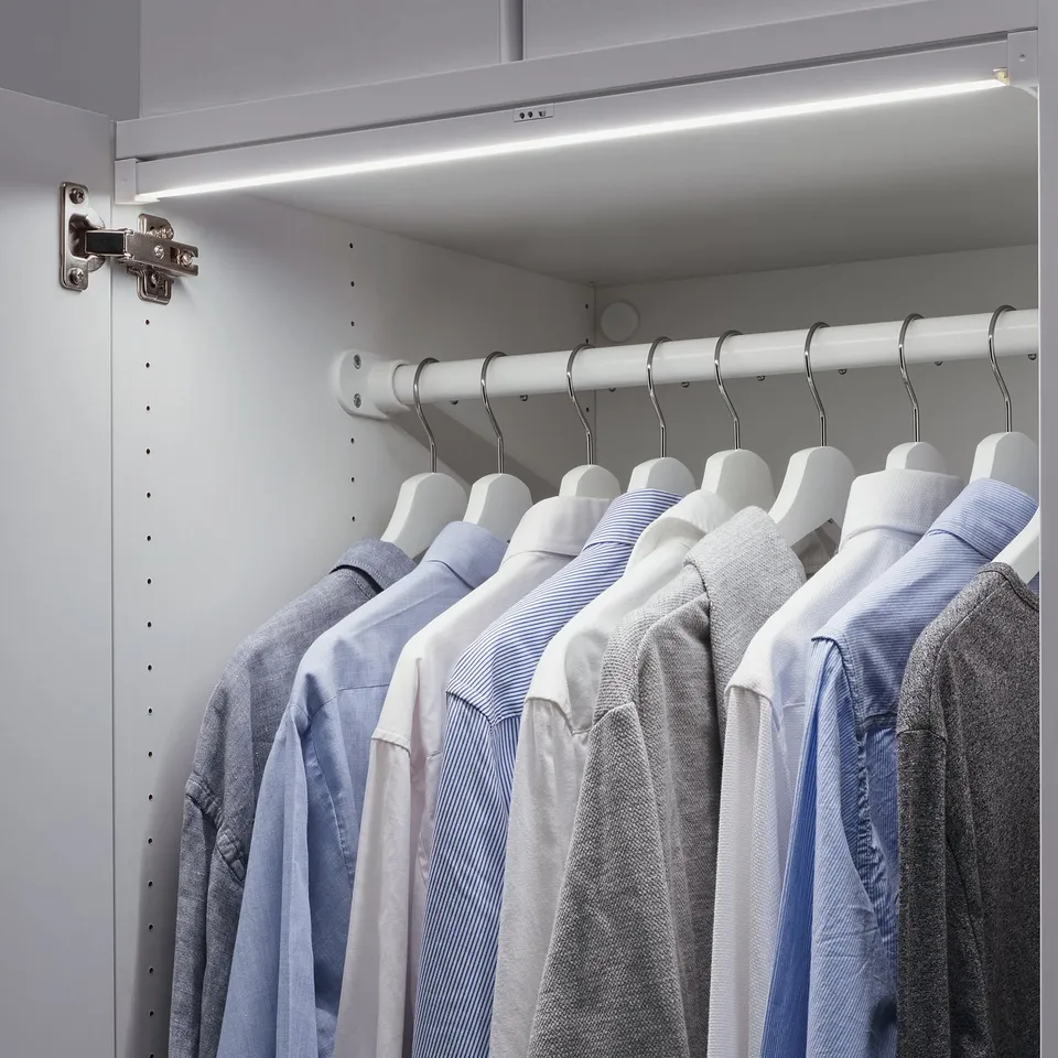 Closet with lit shirts on hangers.
