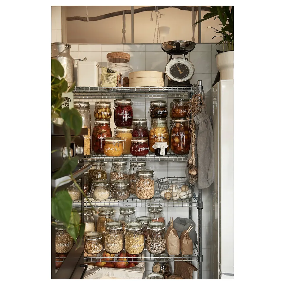 Kitchen shelf unit with various jars and items. Metal frame, wire shelves, storing food. Includes scale and hanging cloth.