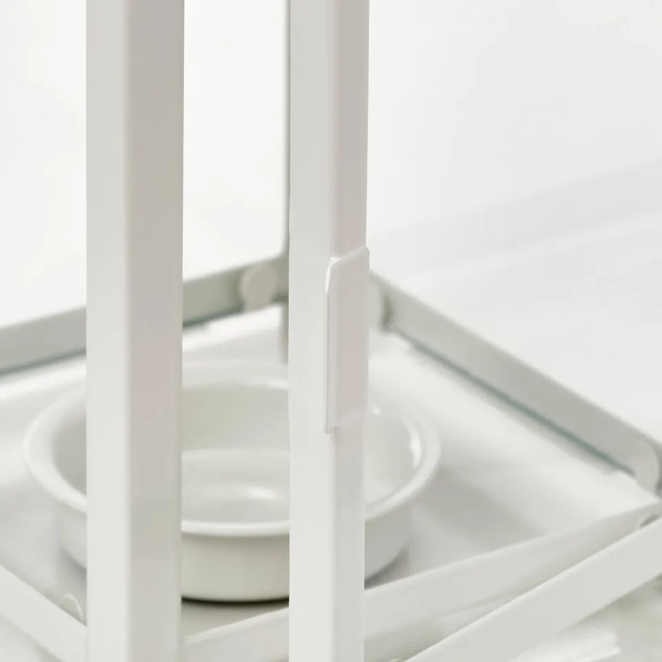 All-white BORRBY lantern holding multiple small candles, evoking cosiness. Glass top and steel construction visible.