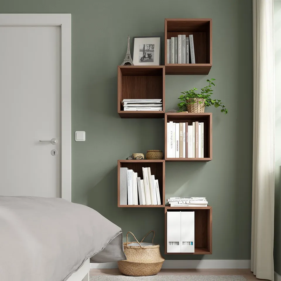 EKET storage unit in bedroom with green wall, holding books, plant, and decor.