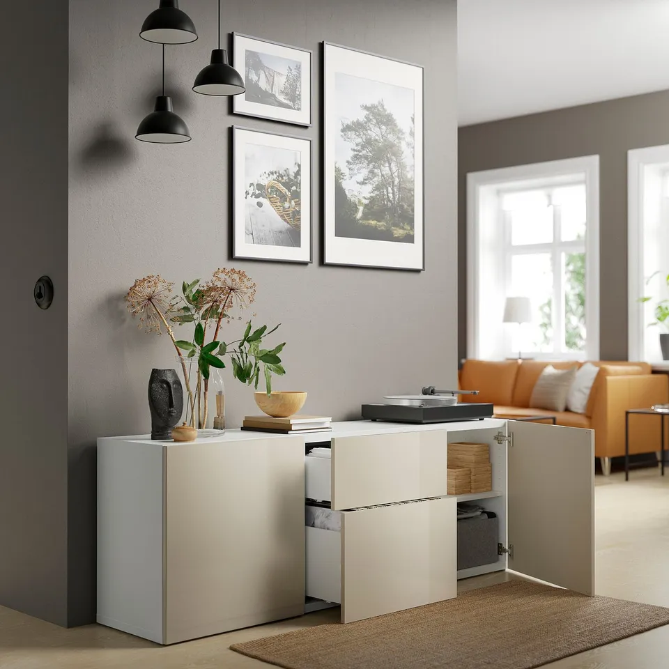Modern living room with white cabinet, open doors showing storage, plant, decorations, orange couch, and large window.