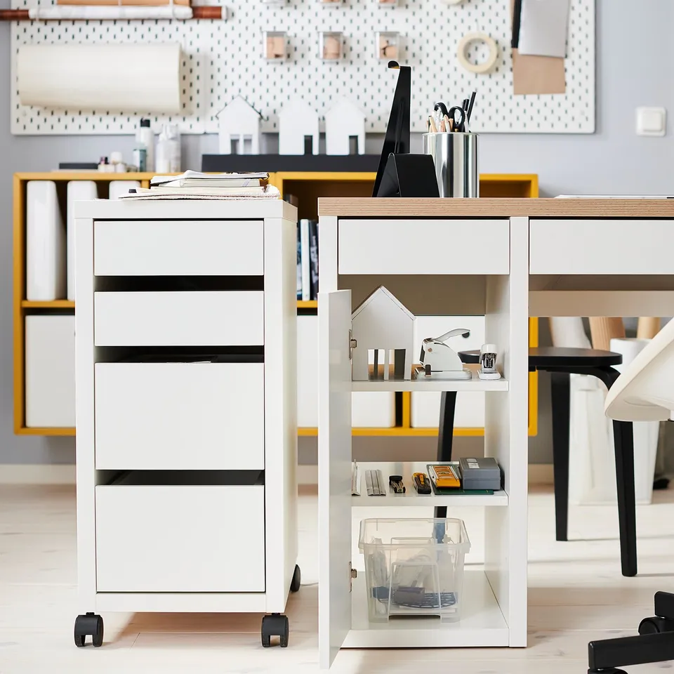 Modern office area with a white MICKE desk and drawer unit, featuring neat organisation with various office supplies.