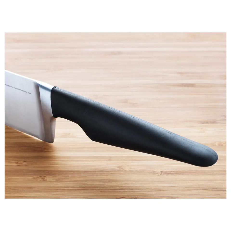 A knife with a black handle on a wooden surface. The blade is sharp and made of stainless steel.