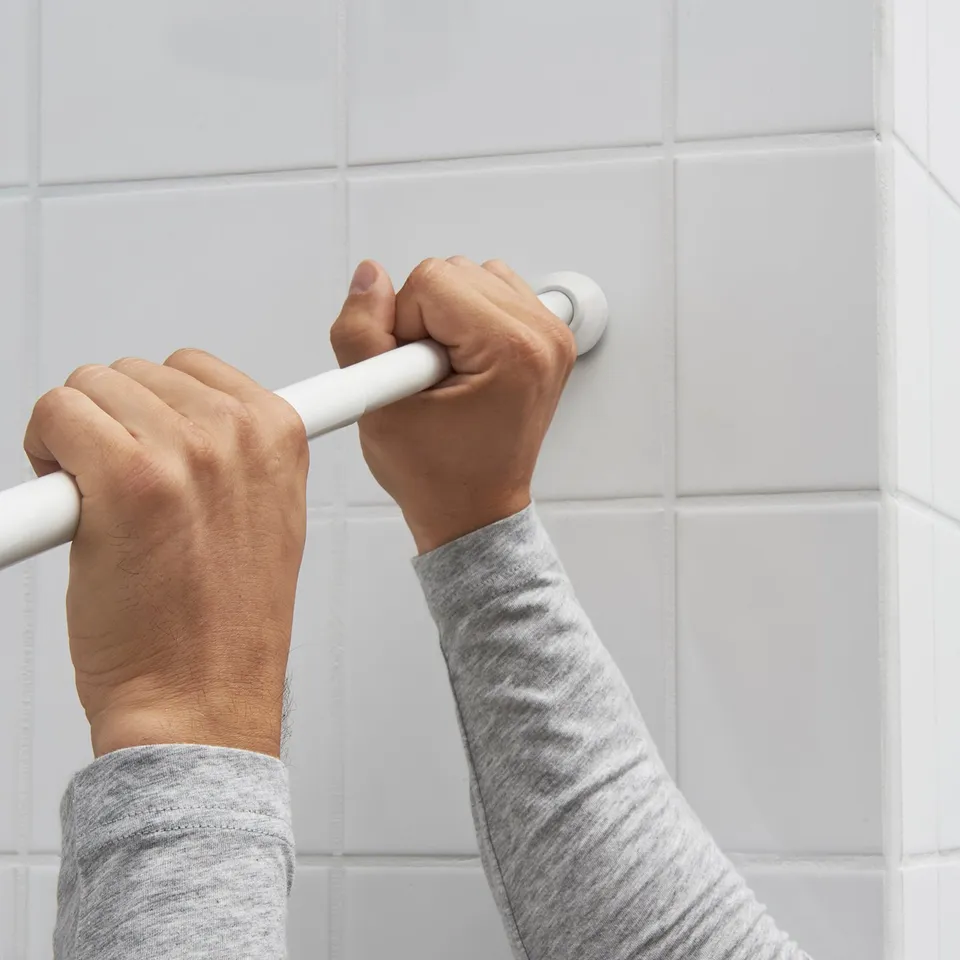 Person installing a spring-loaded shower curtain rod.