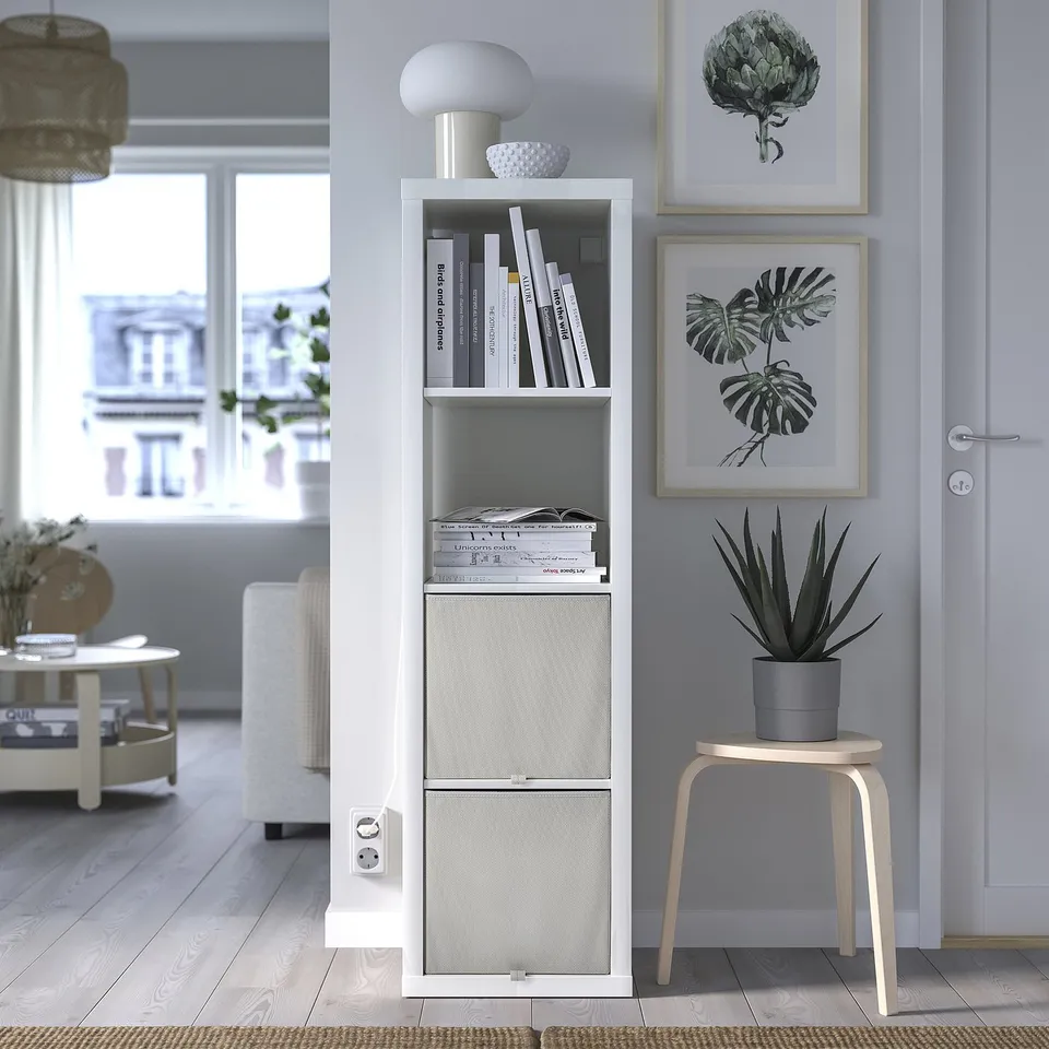 Modern living room with KOSINGEN storage box on kallax shelf, holding books and decor, including plant art and succulent.