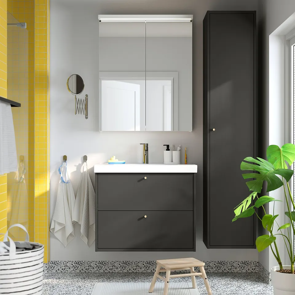 Modern bathroom with grey HAVBÄCK cabinet, large mirror, potted plant, and hanging towels.