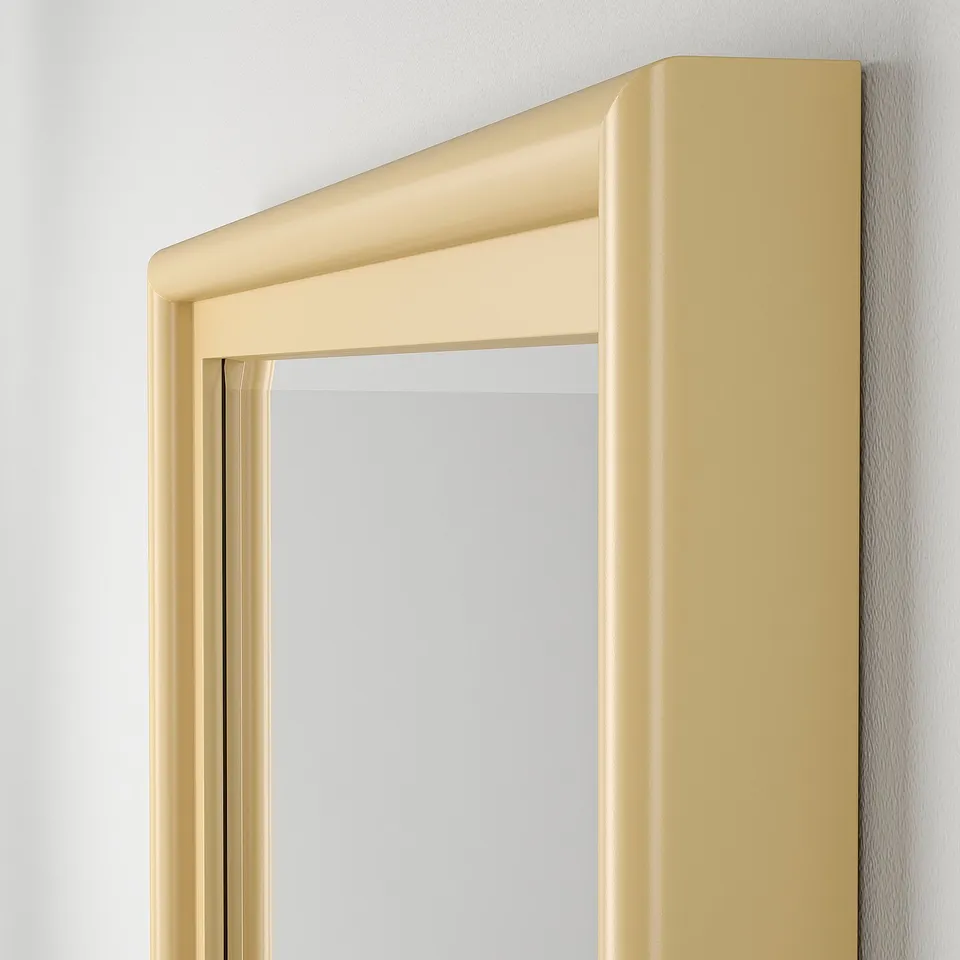 A well-crafted gold mirror hangs on a wall, featuring a solid pine frame with smooth edges and bevelled glass for an elegant look.