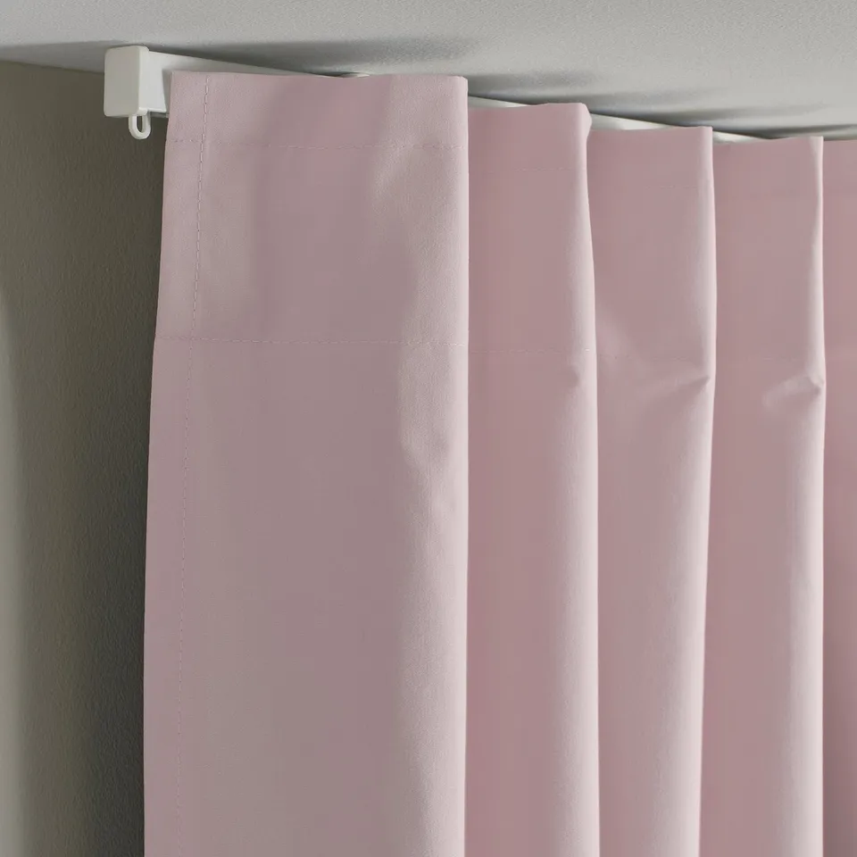 Pink block-out curtains hang neatly, blocking light. Heading tape is same colour for a tidy look.
