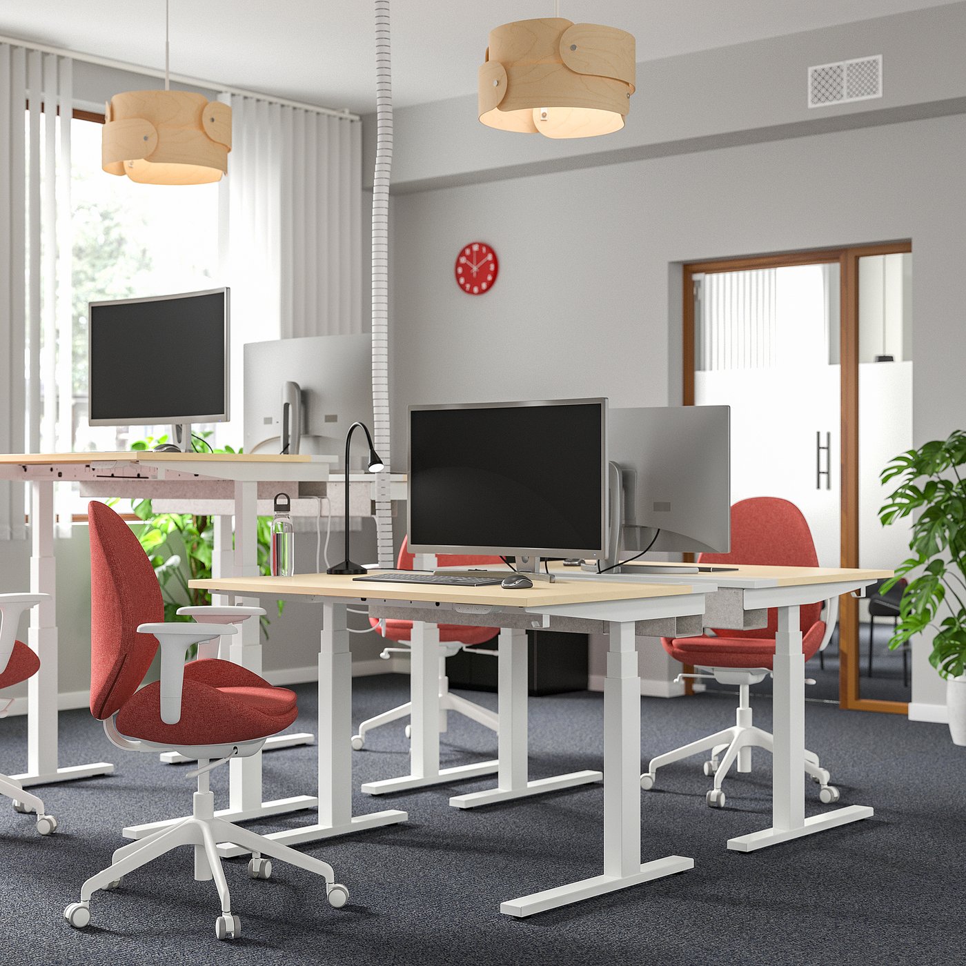 Modern office with MITTZON sit/stand desks, red chairs, dual-motor, plants, wide windows.