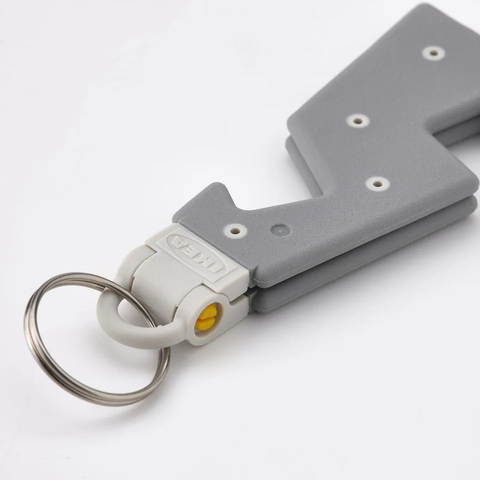 Grey portable phone holder with key ring attached, showing sturdy build and compact design, ideal for travel.