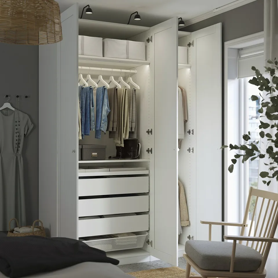 Modern bedroom with open closet displaying clothes, drawers, and lights.