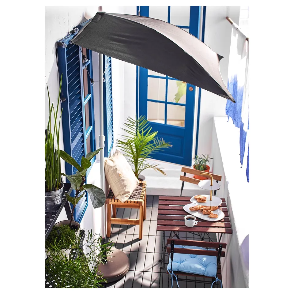 Balcony setup with TÄRNÖ furniture, dark canopy, plants, and breakfast.