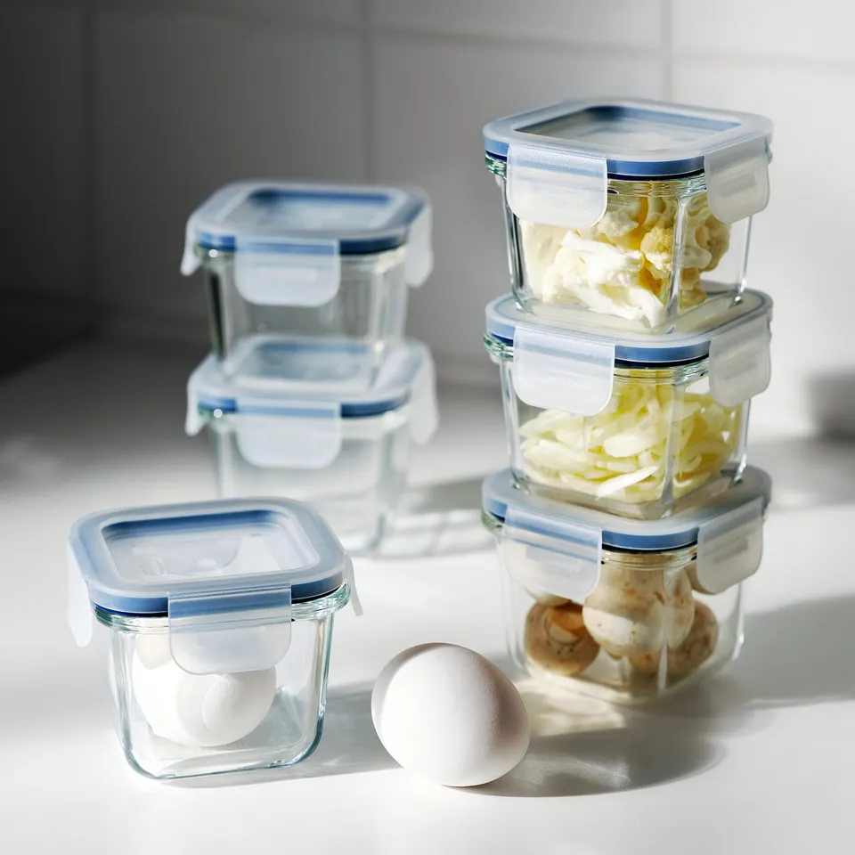 Stacked glass containers with blue lids store food items, keeping contents visible and fresh.