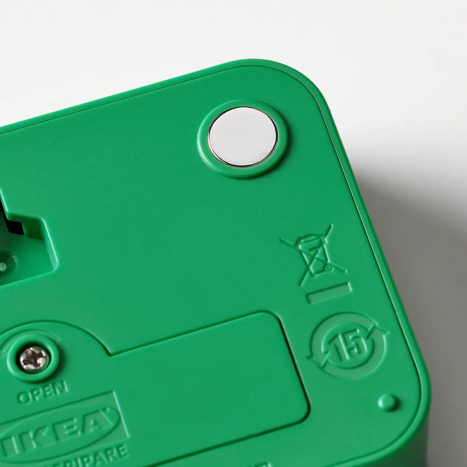Green IKEA LJUNGPIPARE digital clock backside with magnet and embossed symbols.