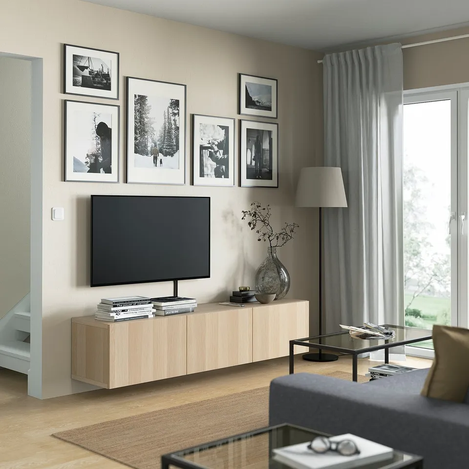 Modern living room with BESTÅ tv bench, flat screen tv, and decorative items. Large windows with curtains create a cosy, organised space.