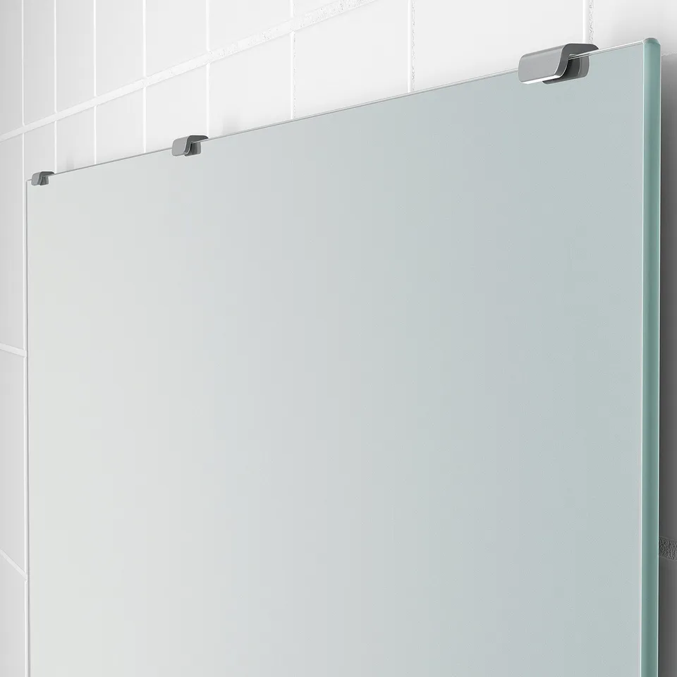 Large frameless mirror mounted on white tiled wall. High-quality glass with clear reflection and sturdy metal fixtures.