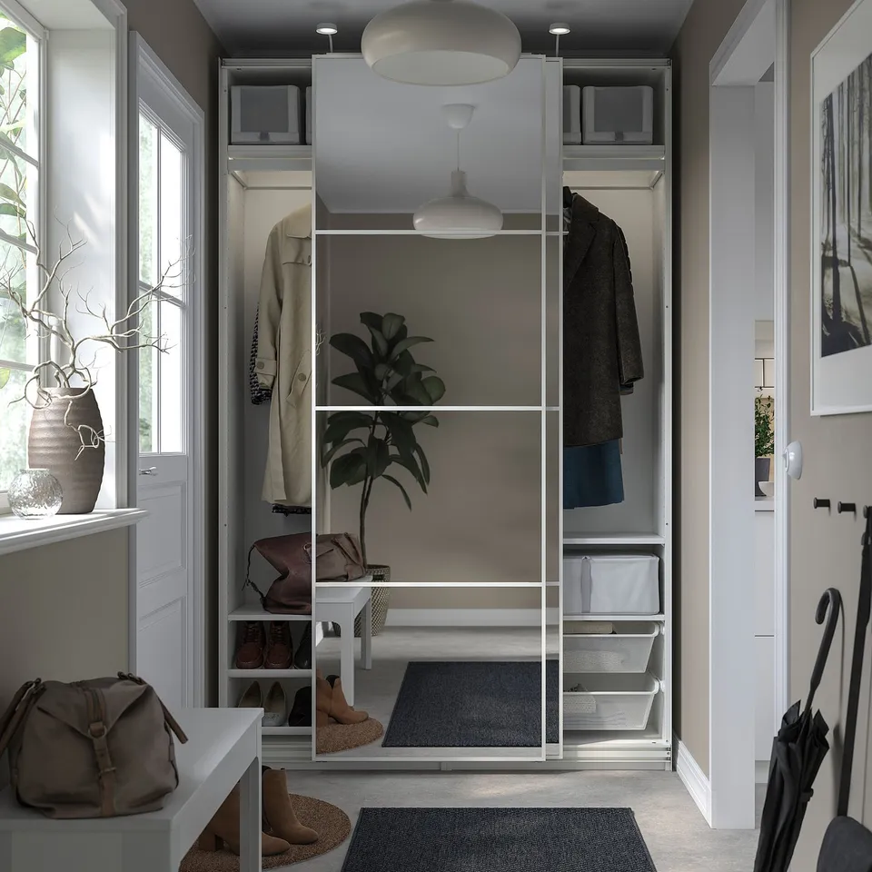 Modern closet with sliding doors, hanging coats, shelves, and storage bins. Includes a bench and rug.