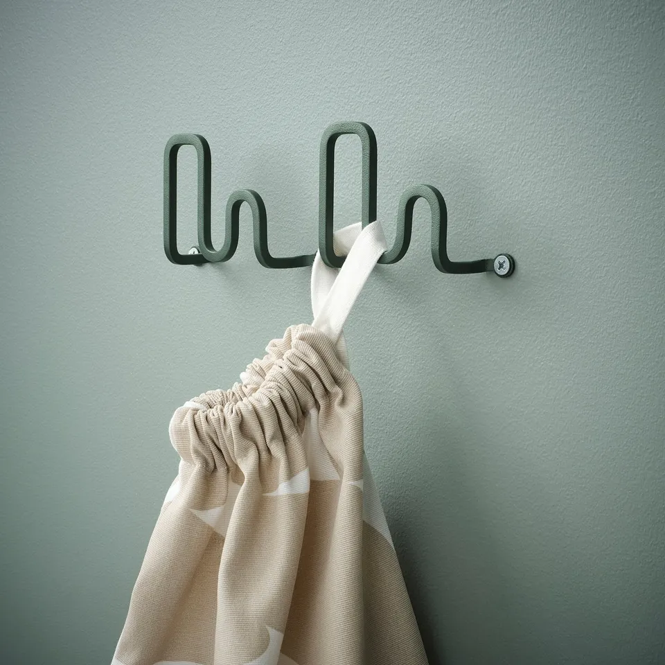 Green wall hook shaped like a wave holding a striped towel.