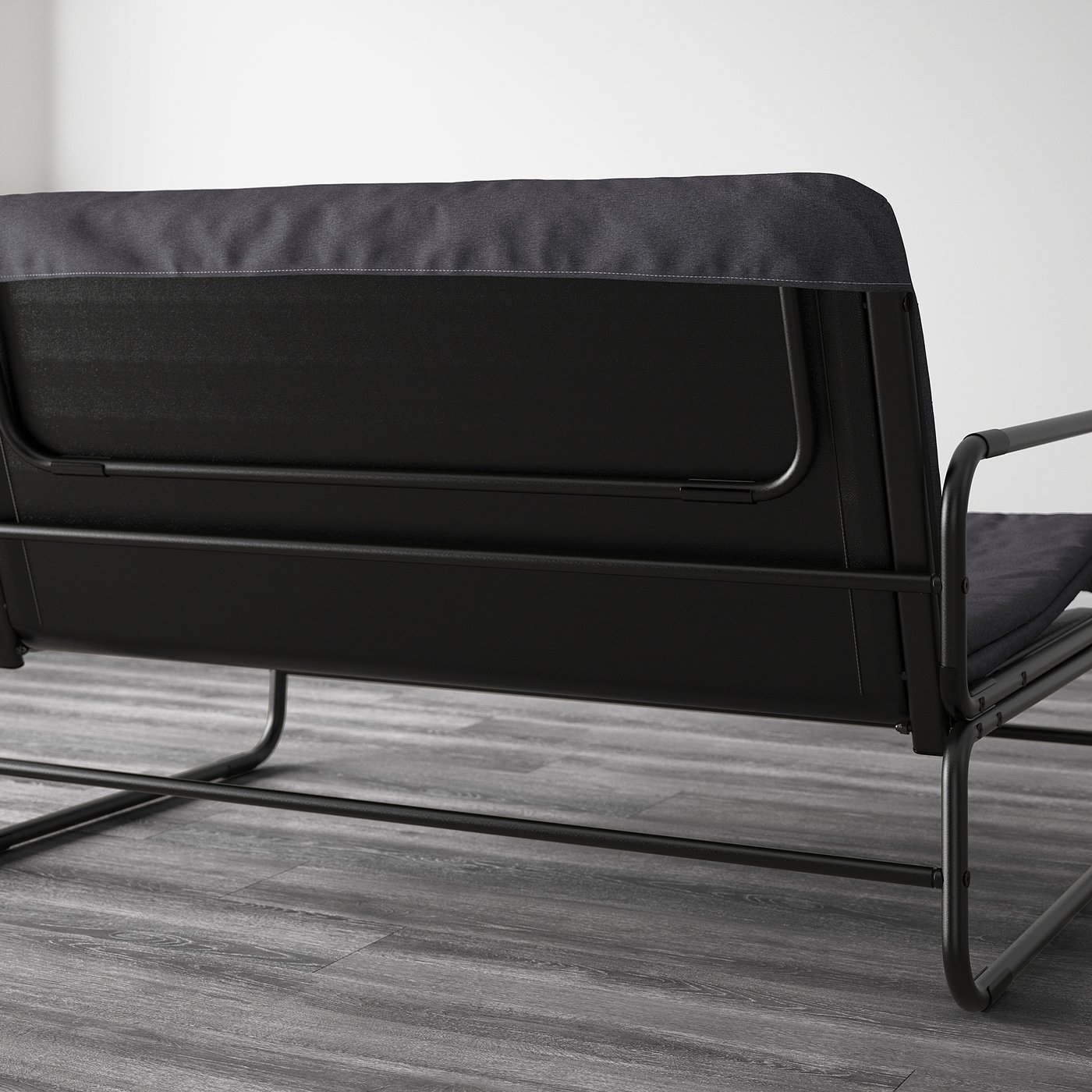 Black sofa bed with metal frame, capable of transforming into a bed for two, shown in a modern room setting.