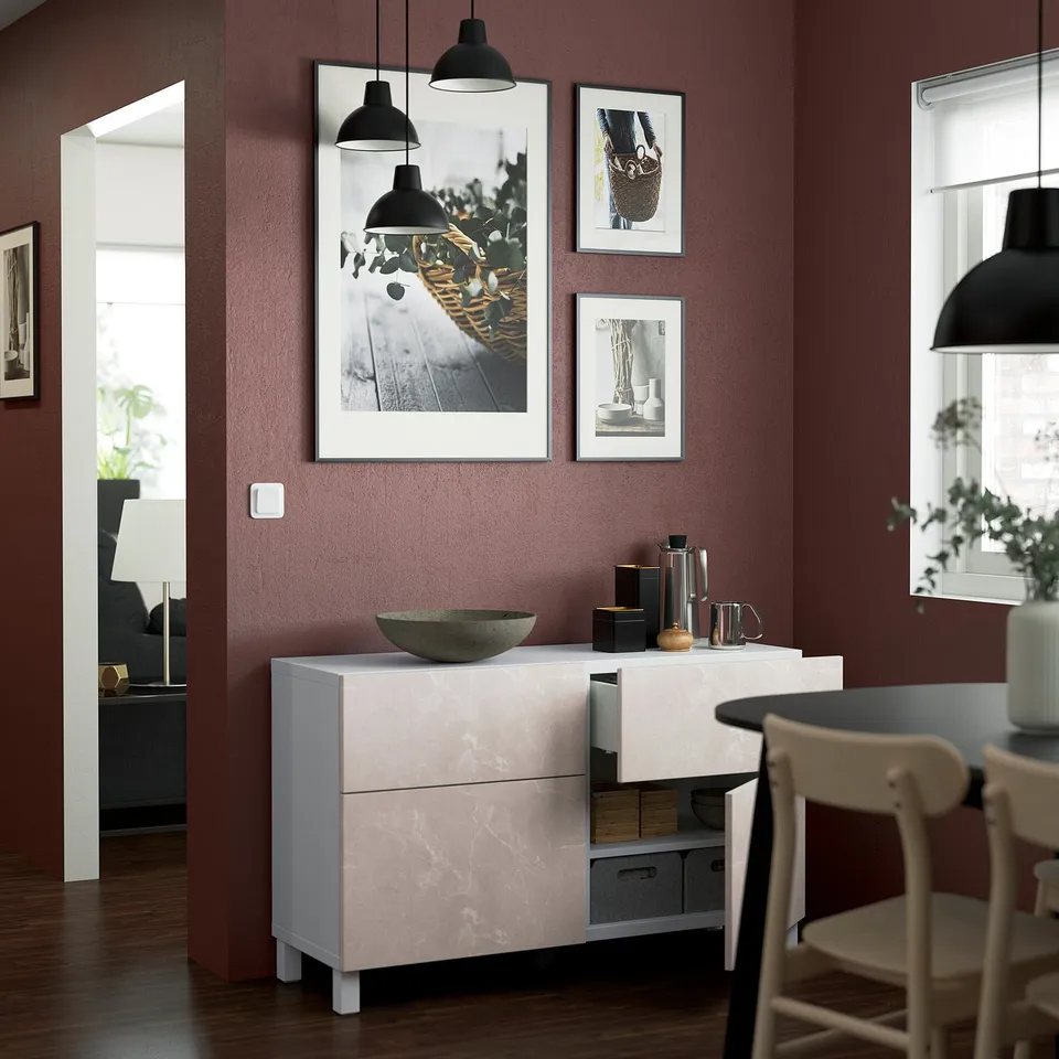 Modern dining room with a white BESTÅ sideboard featuring slide-out drawers and open shelves, topped with a black pendant lamp and framed wall art.