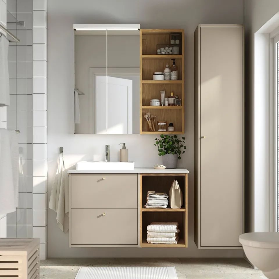 Modern bathroom setup with beige HAVBÄCK vanity, sleek countertop, open shelves, and mirror cabinet, blending practicality and style.