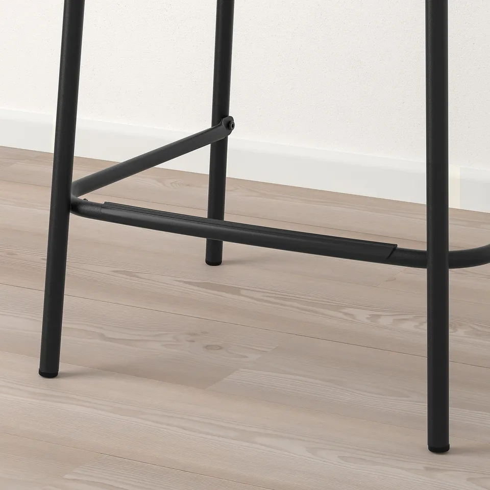 Close-up of modern bar stool with sleek black metal frame and sturdy design on wooden floor.