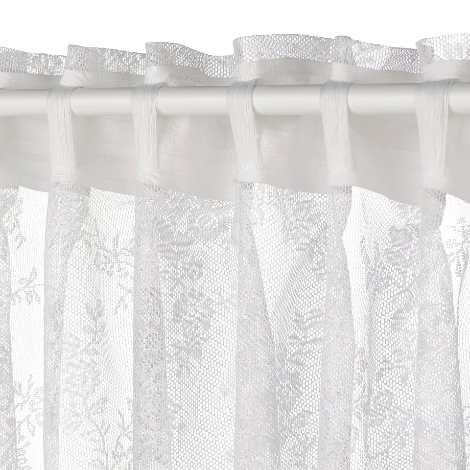 Elegant white lace curtains with floral patterns, sheer fabric, and curved edges hanging gracefully, offering privacy while allowing light through.