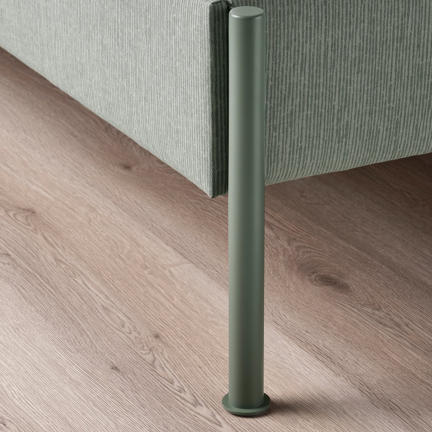 Close-up of modern upholstered bed frame with sleek, green metal leg; soft, striped headboard.