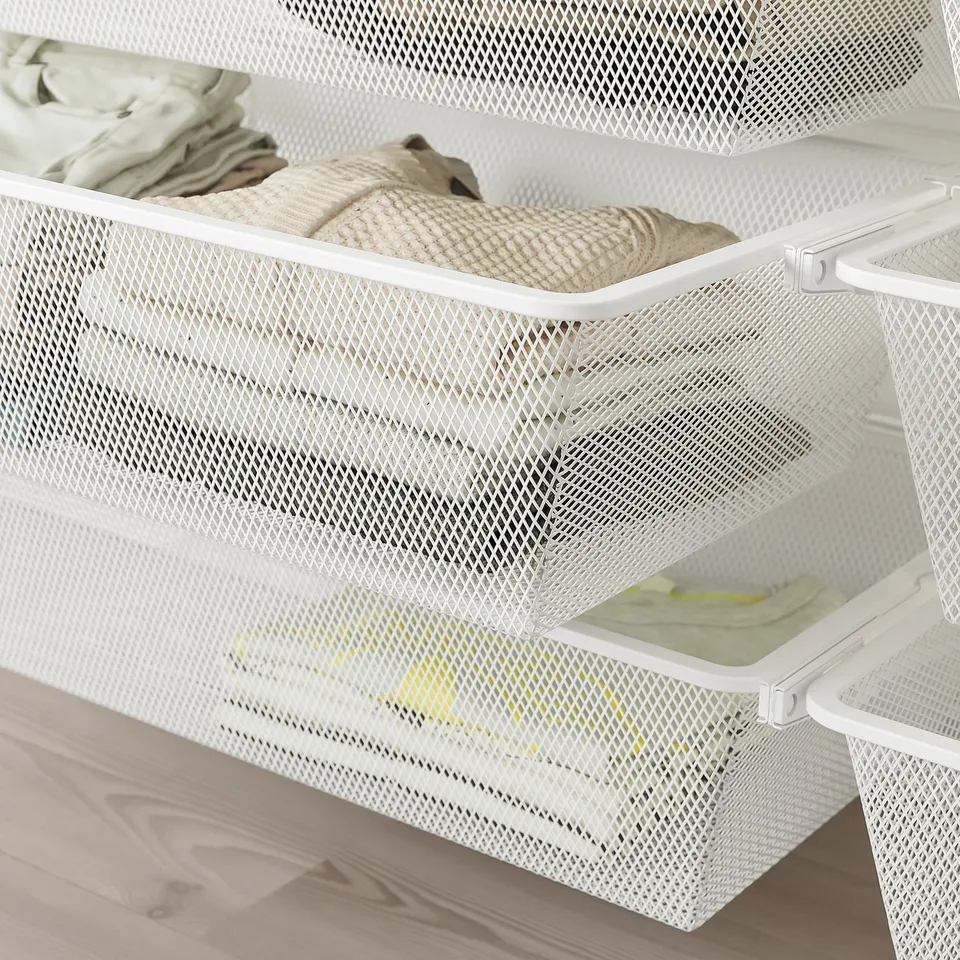 White mesh storage drawers, organising folded clothes, mounted on wall.