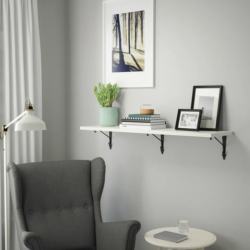 Cosy reading nook with shelf, books, plant, frame, armchair, and side table.