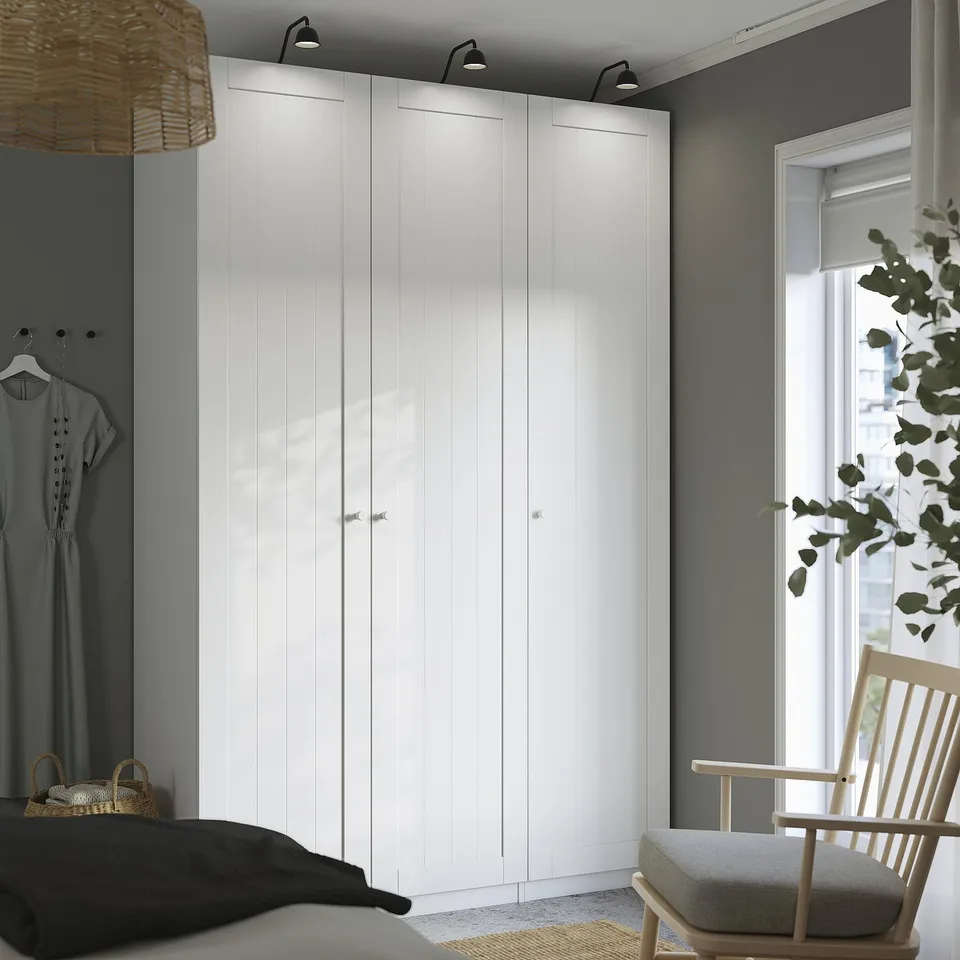 Modern bedroom with large white PAX wardrobe, black bed, wooden chair, and window.