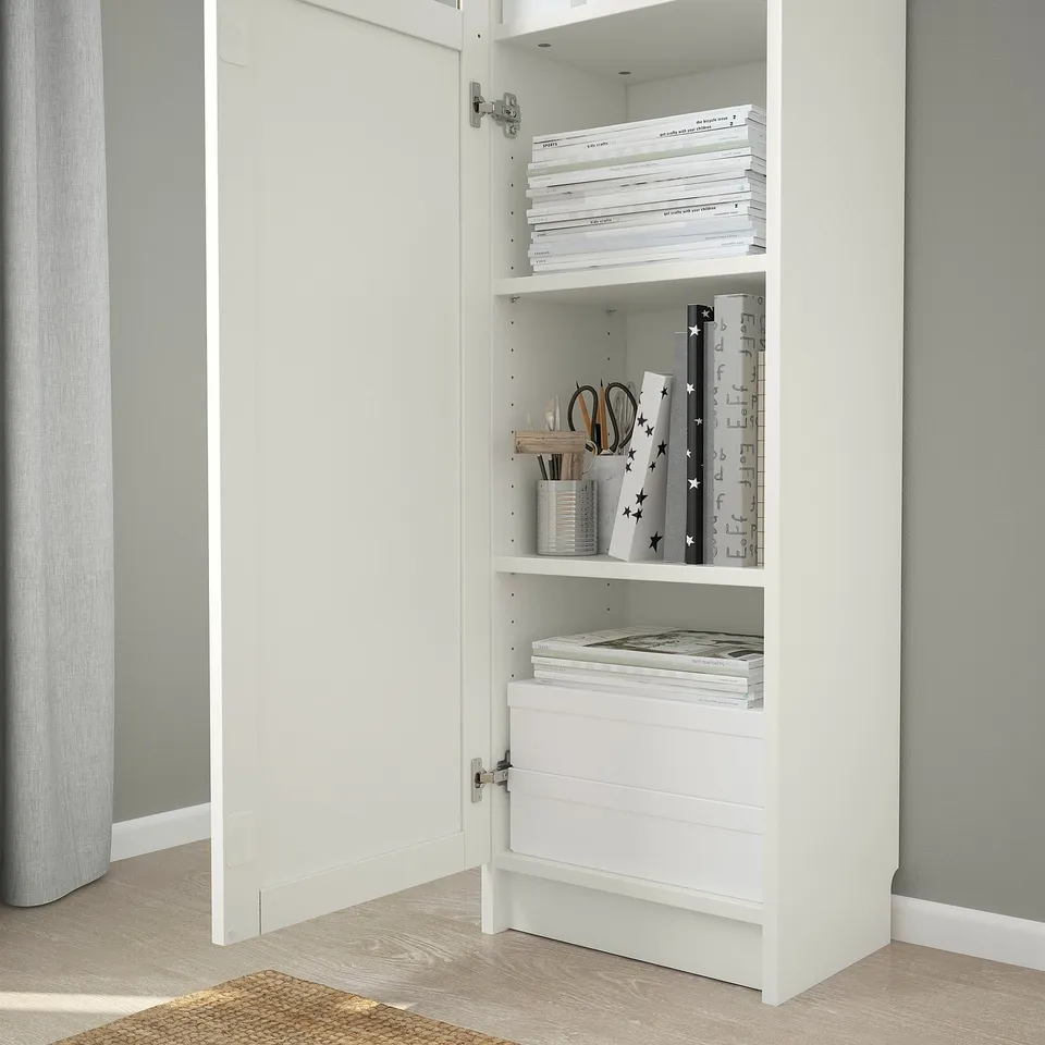 White wooden bookshelf with glass door, storing books and stationery.