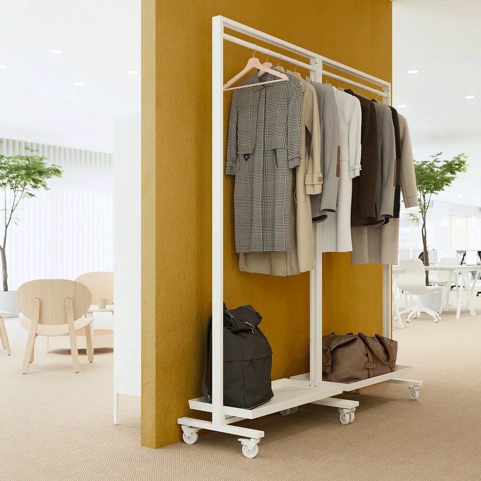 MITTZON: metal coat rack with wheels, holding coats and bags, in room with chairs and yellow wall.