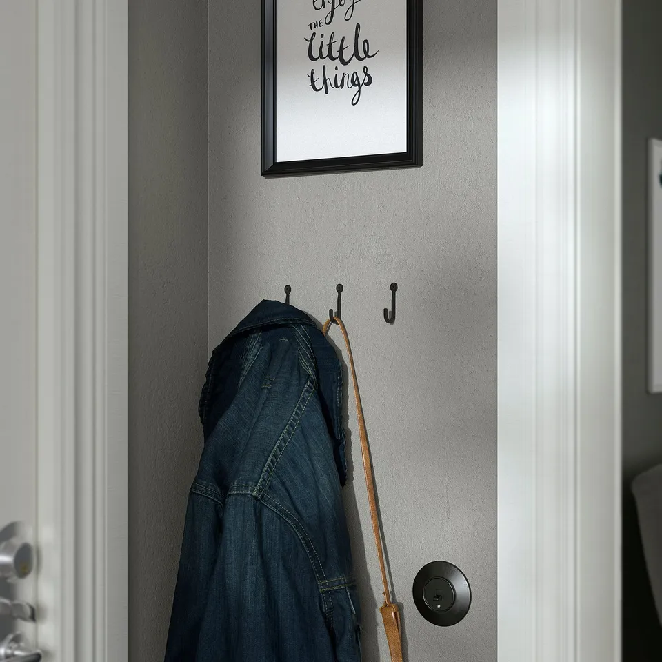A wall-mounted hook holding blue jeans and a brown leather belt.