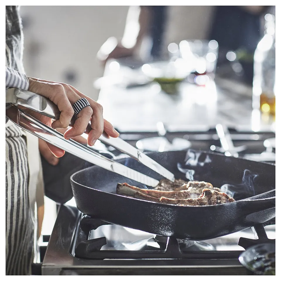 Cooking steak in a VARDAGEN black cast iron pan on a gas stove.