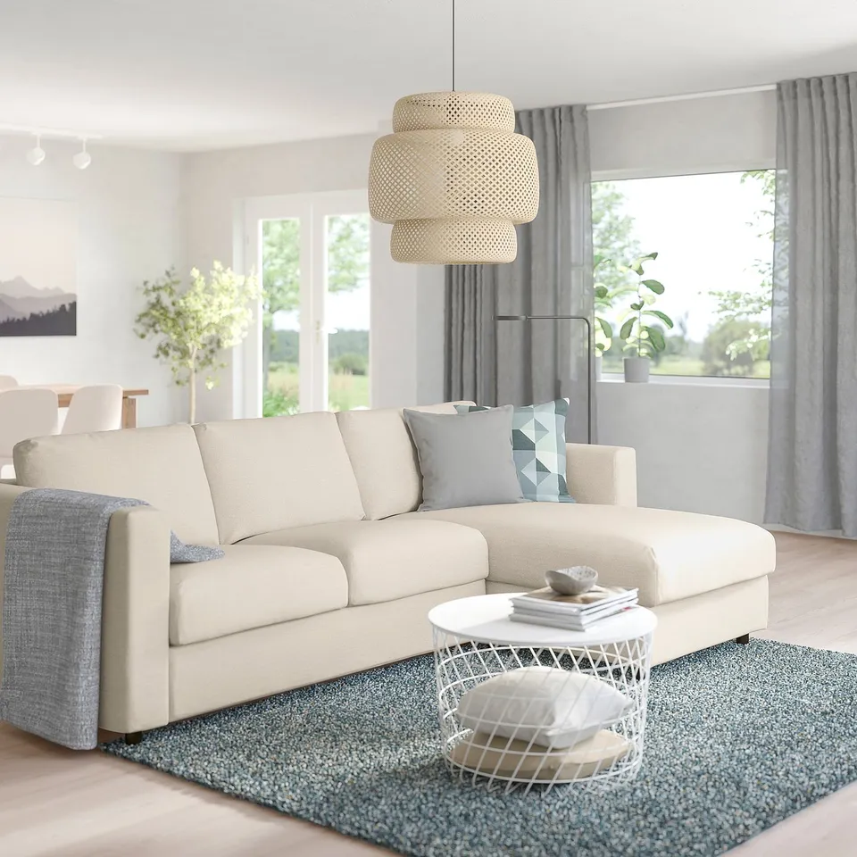 Modern living room: cream VIMLE sectional, large, with grey pillows. Wire coffee table, blue rug, large window, natural light.