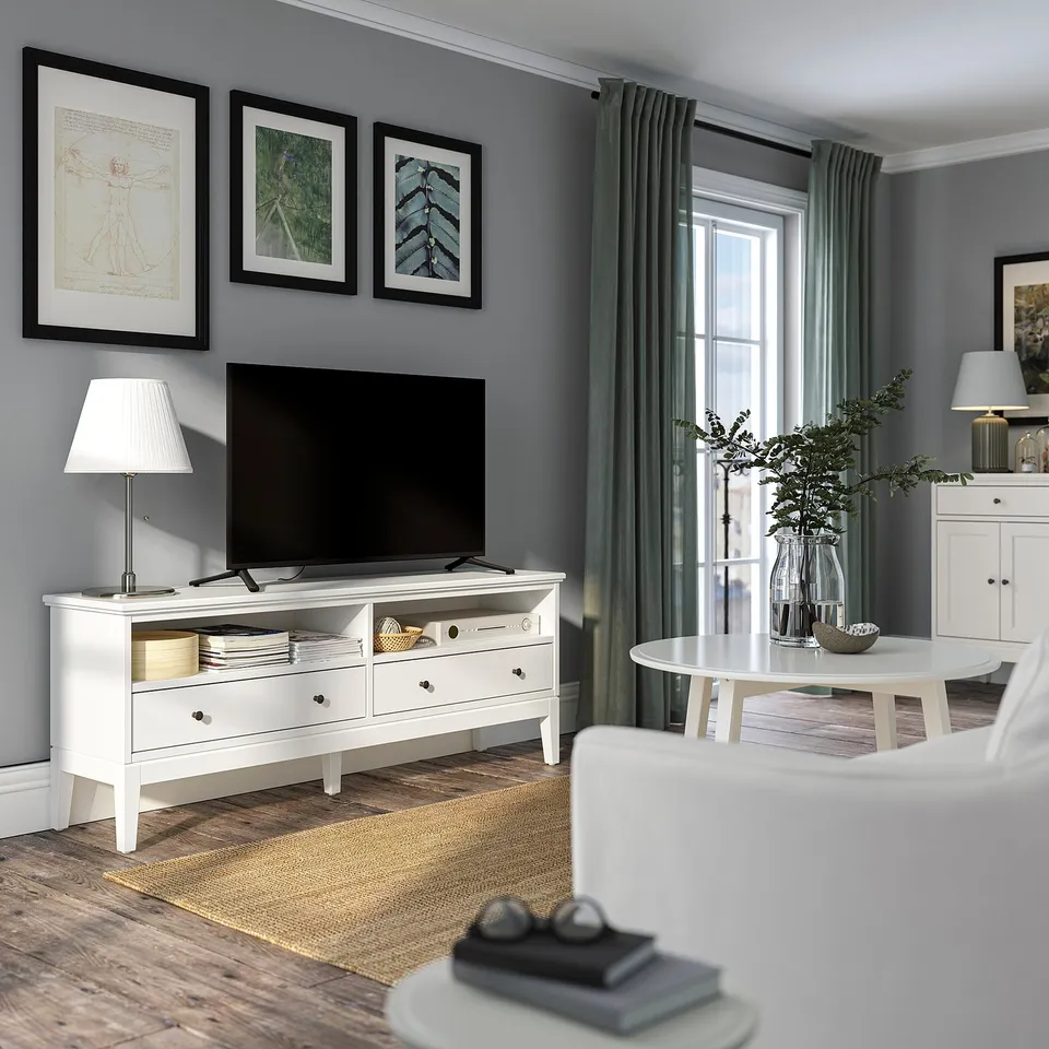 Modern living room with IDANÄS white tv stand, flat screen, lamp, rug, green curtains, and potted plant.