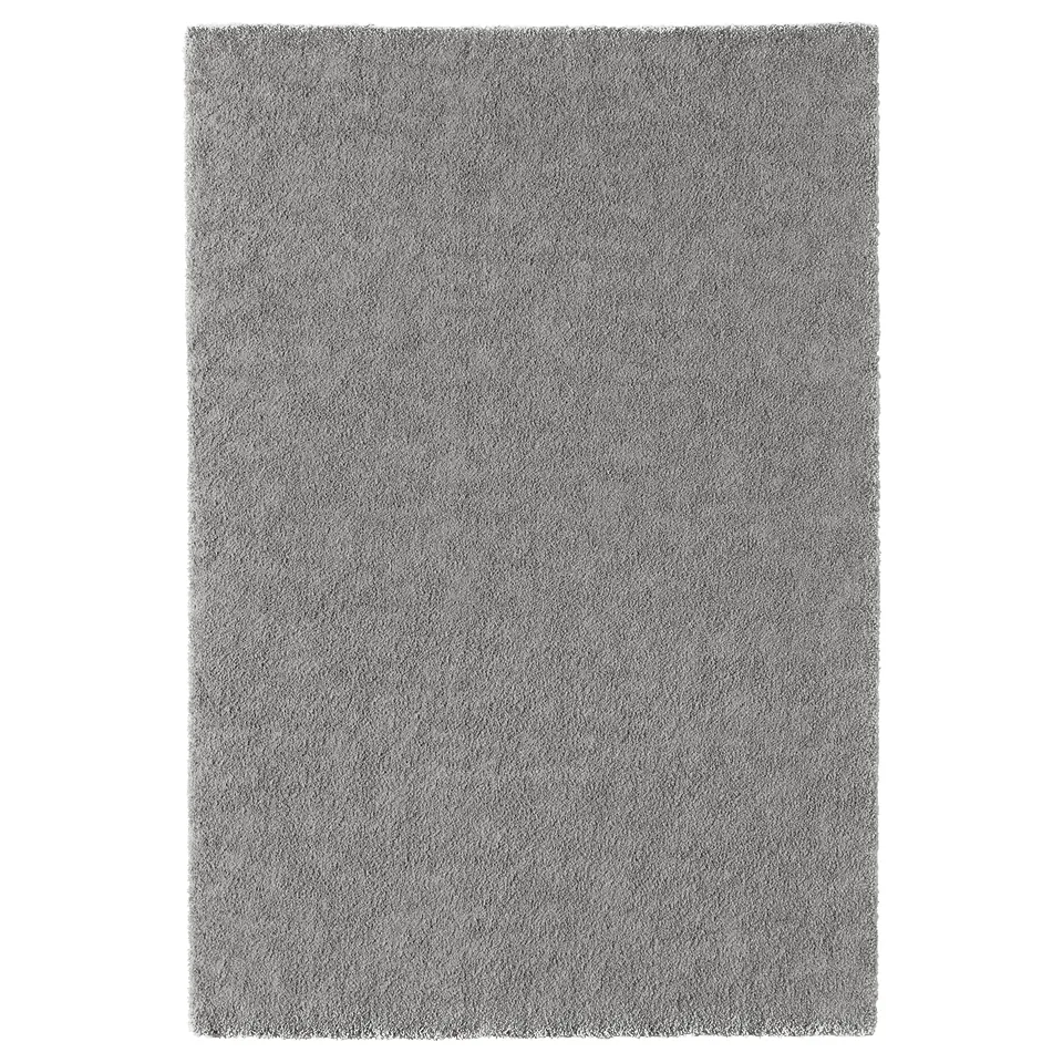 A rectangular, grayish-silver STOENSE rug with a thick, soft pile. Its rectangular and uniformly coloured with no patterns.
