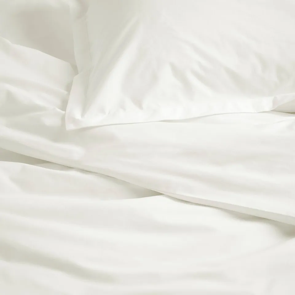 Crisp white cotton bedding, neatly arranged with smooth sheets and pillowcases.