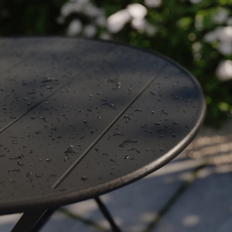 Black outdoor table with water droplets, part of the SUNDSÖ collection, folds for easy storage.